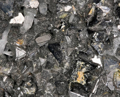 Close-up of a cluster of shiny, dark crystals with a textured, glittery surface, showcasing various crystal shapes and formations.