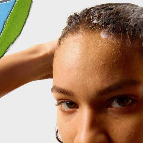 En person med vått hår applicerar en hårprodukt, med en fargglad sonderriven papperssektion i bakgrunden.