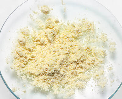 A close-up view of a fine, yellowish powder spread out on a clear glass plate.
