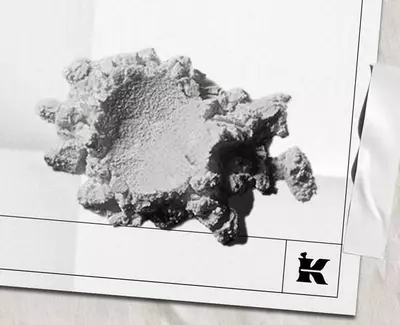 Ett texturerat, oregelbundet format vitt mineral- eller materialfragment vilande på en ljus bakgrund, med en liten logotyp langst ned till hoger.