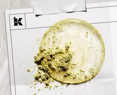 En cirkular flack av ljus gradde med en texturerad hog av gront pulver, presenterad på ett vitt ark markt med en logotyp.