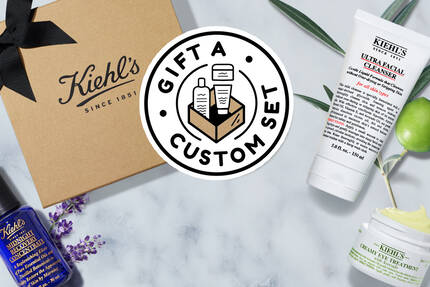 Bild av Kiehl's present set med produkter på en marmorplatta, inklusive hudvårdsprodukter och en papperspåse.