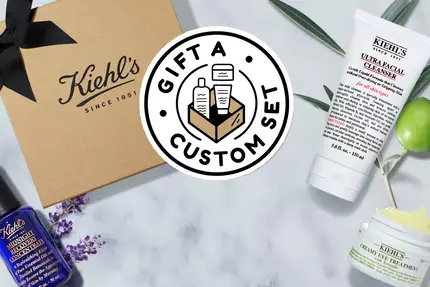 Bild av Kiehl's present set med produkter på en marmorplatta, inklusive hudvårdsprodukter och en papperspåse.