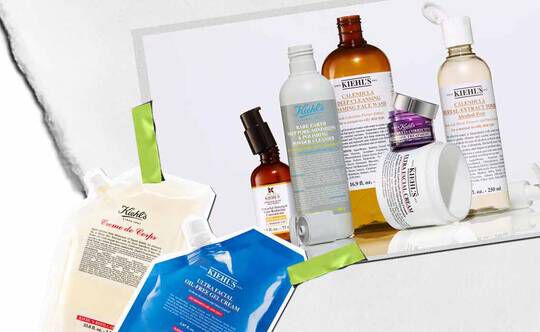 En samling av Kiehl's hudvårdsprodukter, inklusive lotioner och serum, konstnarligt arrangerade med livfulla forpackningar och etiketter synliga.