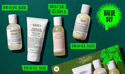 En flat lay-bild på en morkgron bakgrund visar ett Kiehl's produktset, framhavt med en ljusgron grafik som visar vardepriset. Setet inkluderar fyra produkter i resestorlek: till vanster, en 75 ml flaska Kiehl's Amino Acid Shampoo; bredvid den, en 75 ml tub Kiehl's Amino Acid Conditioner; i mitten, en 65 ml deluxe provflaska av Kiehl's Bath and Shower Liquid Body Cleanser i doften 'Grapefrukt'; och till hoger, en 75 ml flaska Kiehl's Creme de Corps. En gron Kiehl's presentask med en framtradande bandgrafik ar delvis synlig i bildens nedre hogra horn.