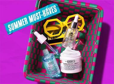 En lila banner med en gron och rosa flatad korg fylld med Kiehl's hudvårdsprodukter och gula solglasogon, med blå tejp dar det står 'SUMMER MUST-HAVES'.