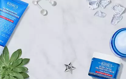 Produkter for hudvård från Kiehl's, inklusive ansiktskram, toner och gel, placerade på en marmorliknande yta med citronskivor och isbitar runtom.