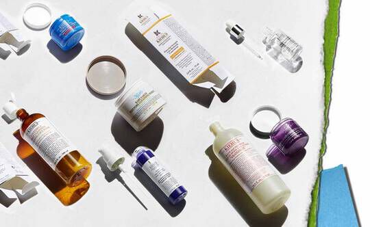 En rad olika hudvårdsprodukter visas mot en ljus bakgrund, inklusive flaskor, burkar och droppflaskor i olika farger och former.