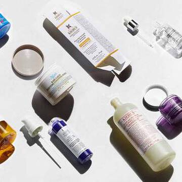 En rad olika hudvårdsprodukter visas mot en ljus bakgrund, inklusive flaskor, burkar och droppflaskor i olika farger och former.