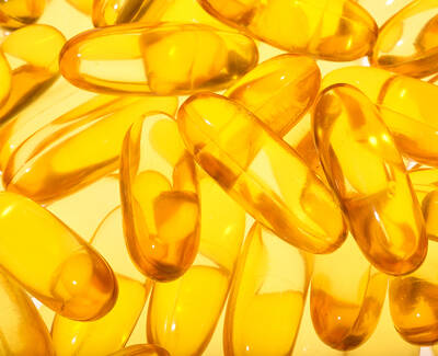 A close-up of transparent yellow gel capsules scattered on a light background.