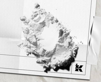 White powder ingredient scattered on white paper packaging with the Kiehl’s logo.