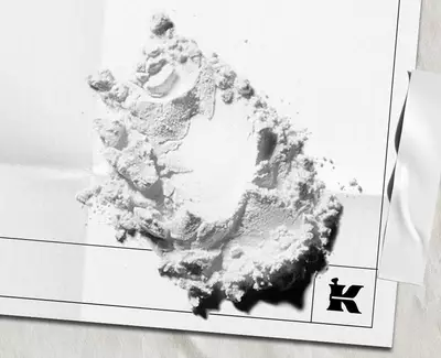 White powder ingredient scattered on white paper packaging with the Kiehl’s logo.​