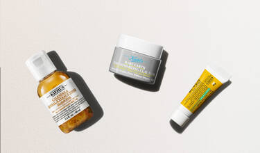 Tre hudvårdsprodukter från Kiehl's mot en ljus bakgrund: Calendula-toner, Rare Earth-lermask och en liten gul tub.