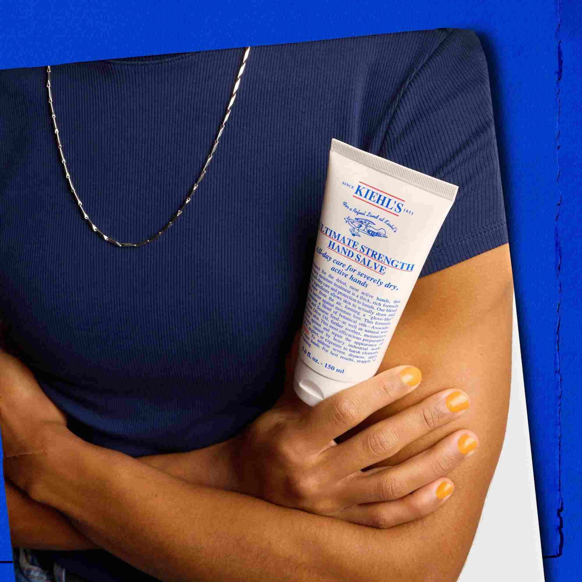 Modell som håller en tub Kiehl's Ultimate Strength Hand Salve