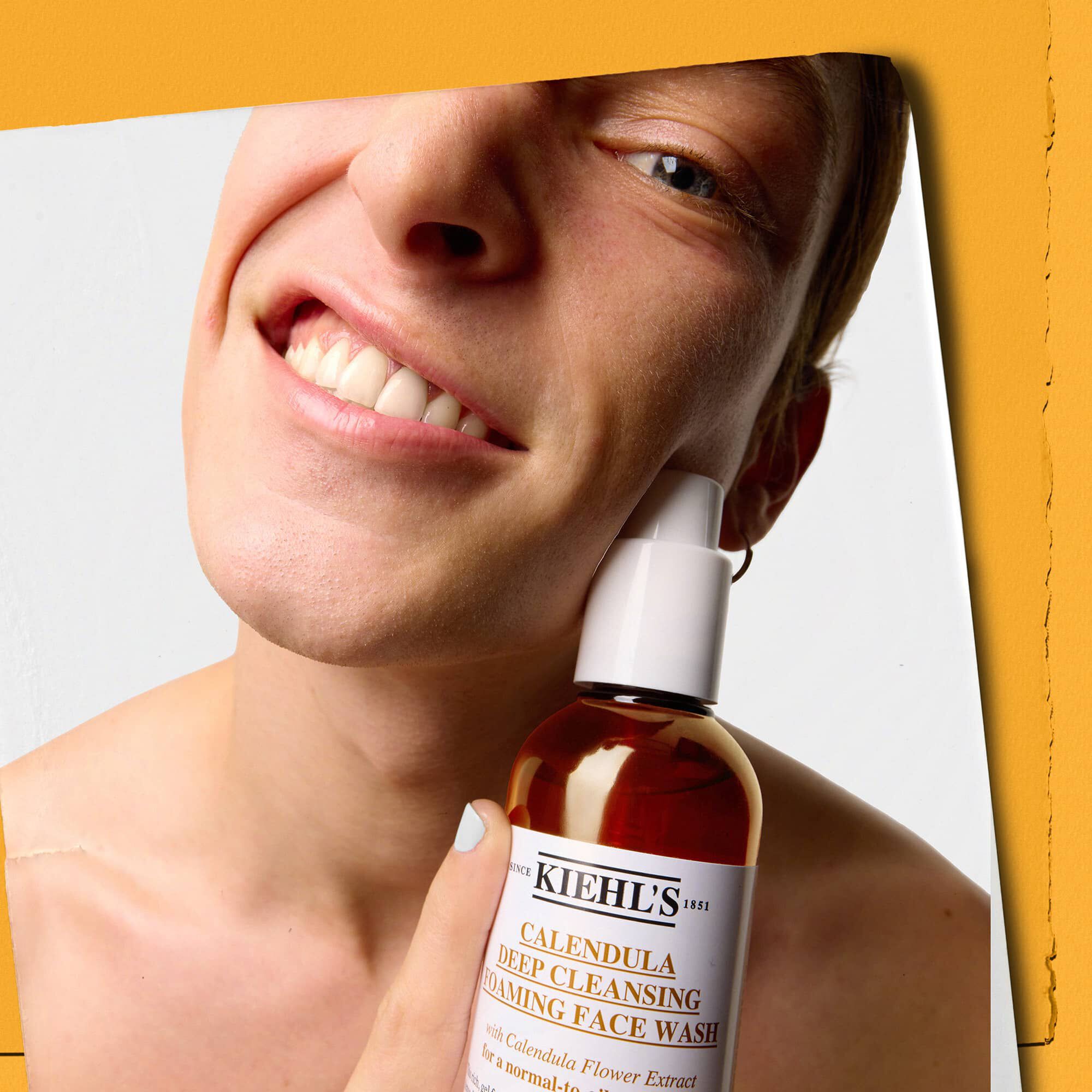 Modell som håller en flaska Kiehl's Calendula Deep Cleaning Foaming Face Wash