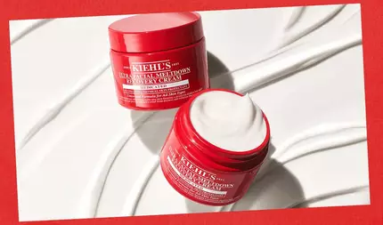 Två oppna roda burkar med Kiehl's Ultra Facial Meltdown Recovery Cream visades mot en vit bakgrund med slata kramsvirvlar, mot en rod kant.