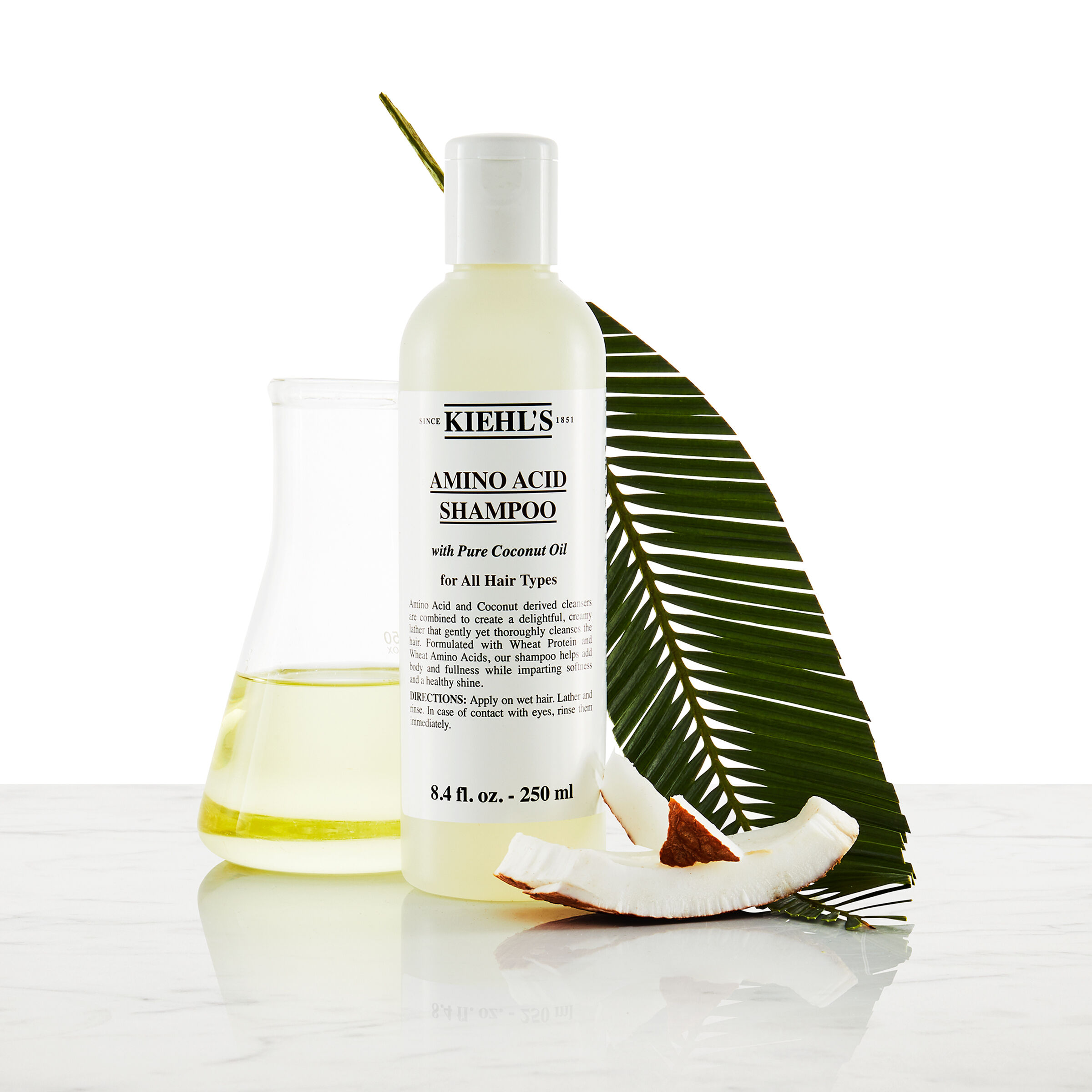 Modell med mustasch och en flaska Kiehl's Amino Acid Shampoo