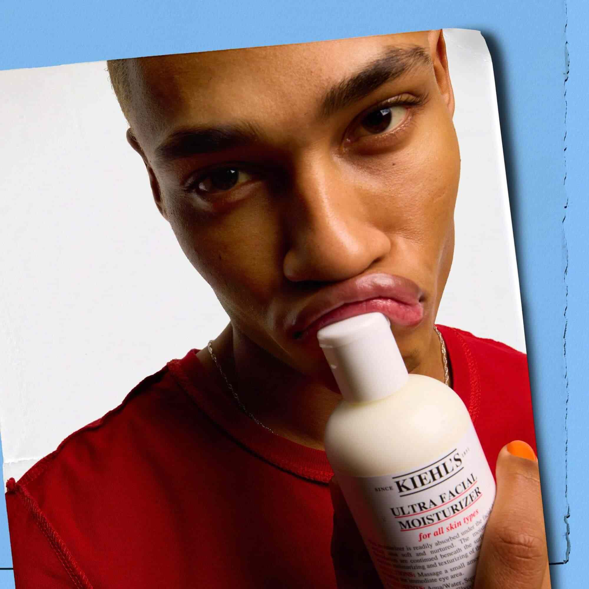 Modell som trycker en flaska Kiehl's Ultra Facial Moisturizer mot sina lappar