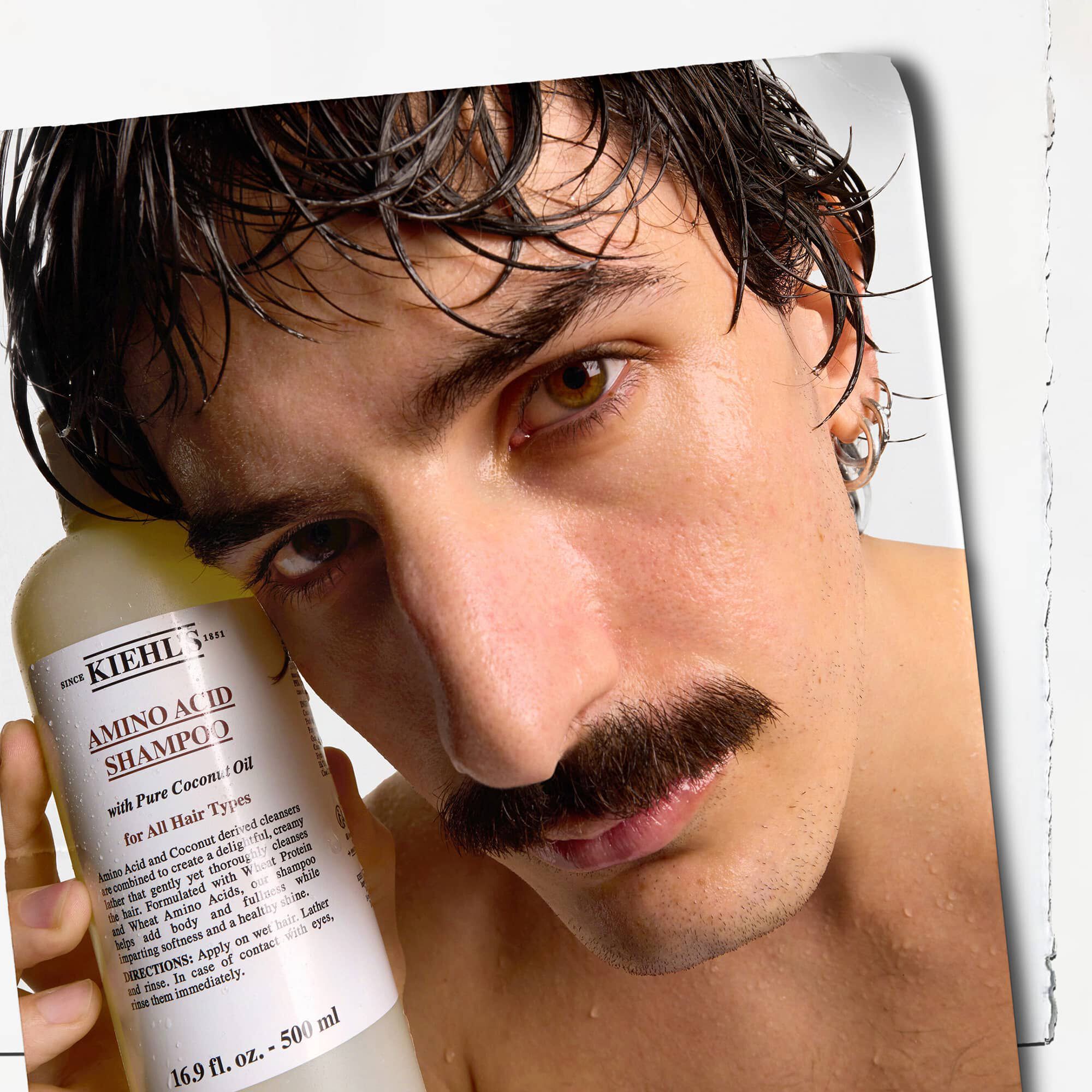 Modell med mustasch och en flaska Kiehl's Amino Acid Shampoo