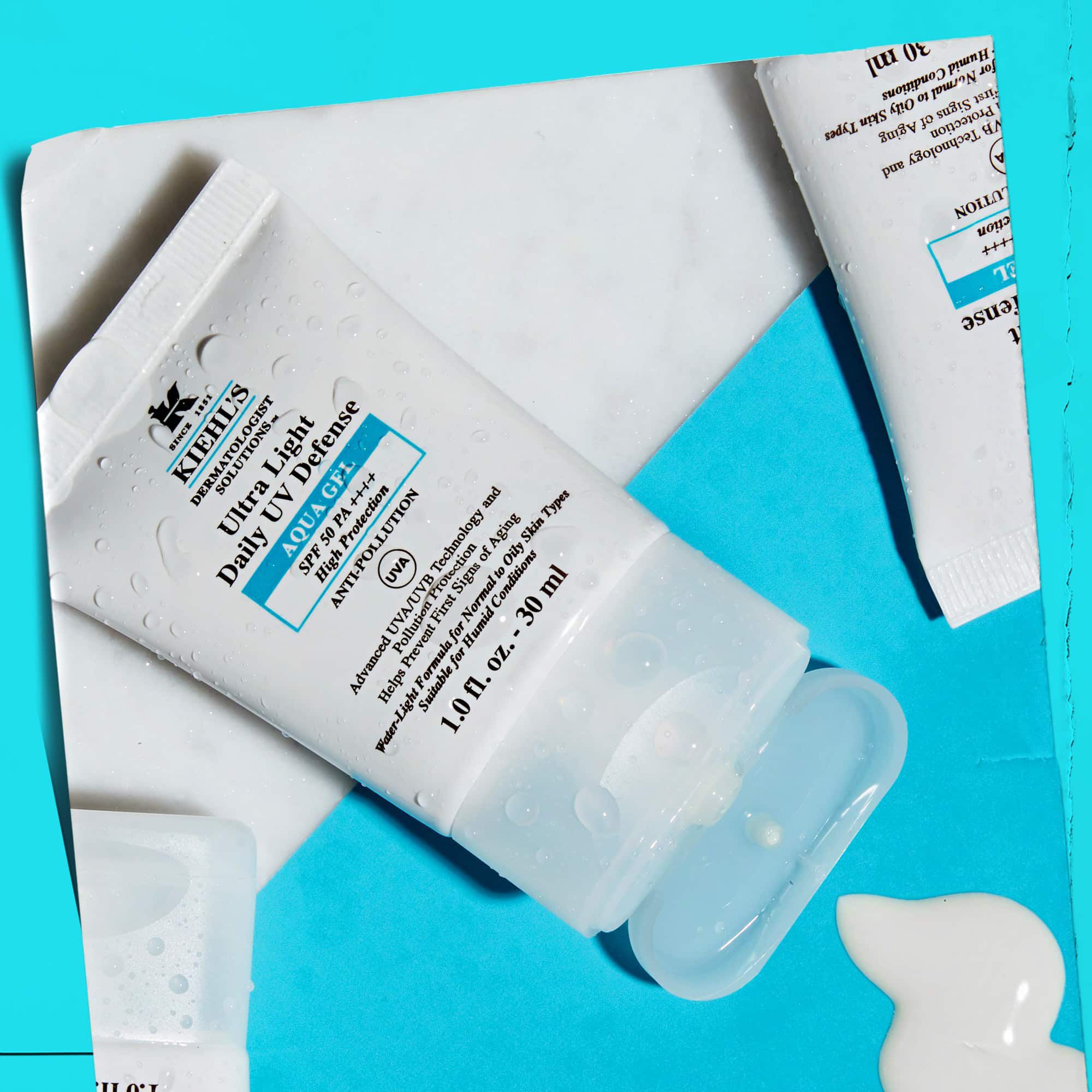 En flat-lay av flera Ultra Light Daily UV Defense Aqua Gel-tuber på en marmoryta, vilket visar deras livsstilsattraktion.